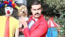 circus tent, clown, man, appears, white, holding dog, dressed like circus ringleader, his expression is like he is possibly in charge