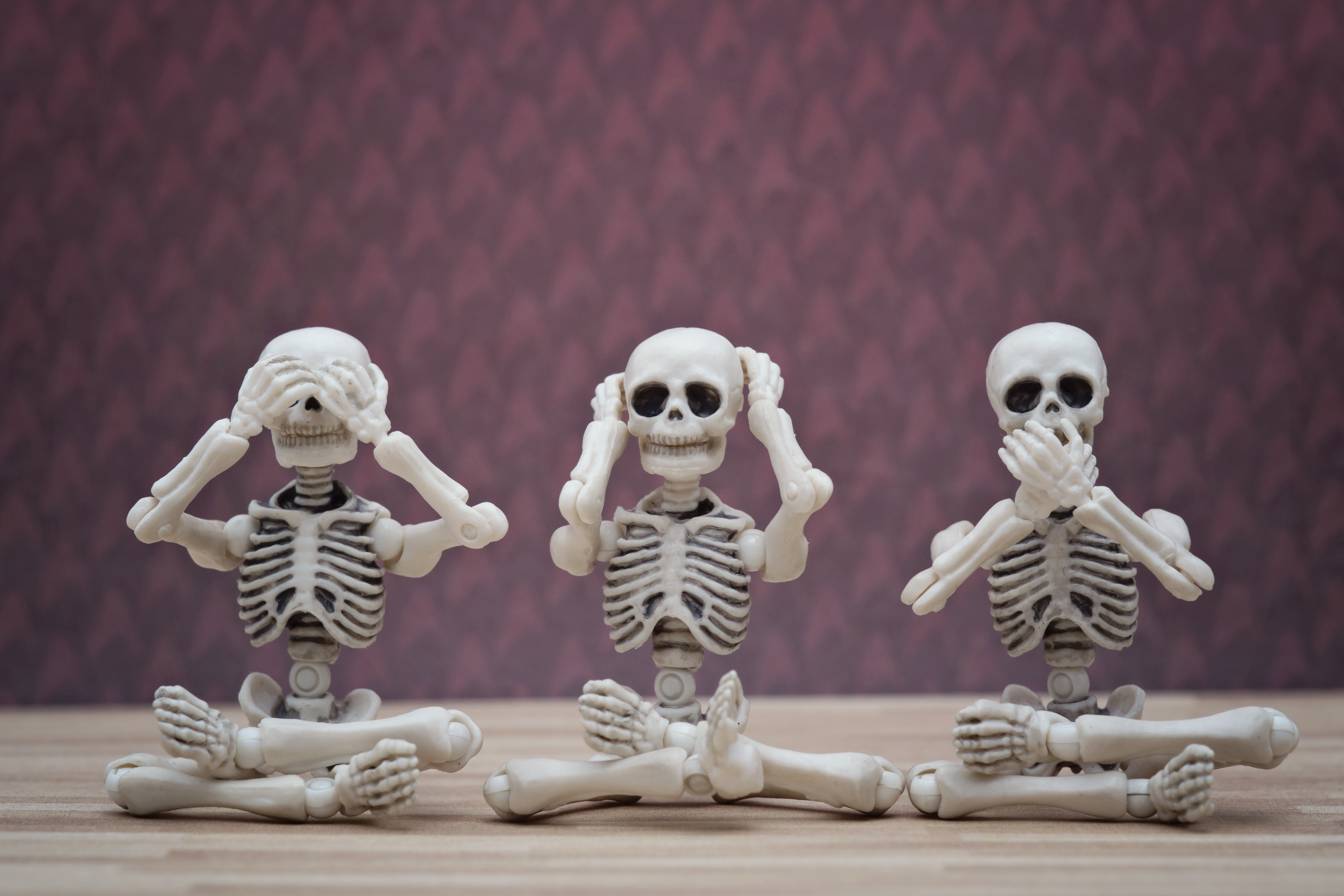 Three skeletons covering eyes, ears, and mouth