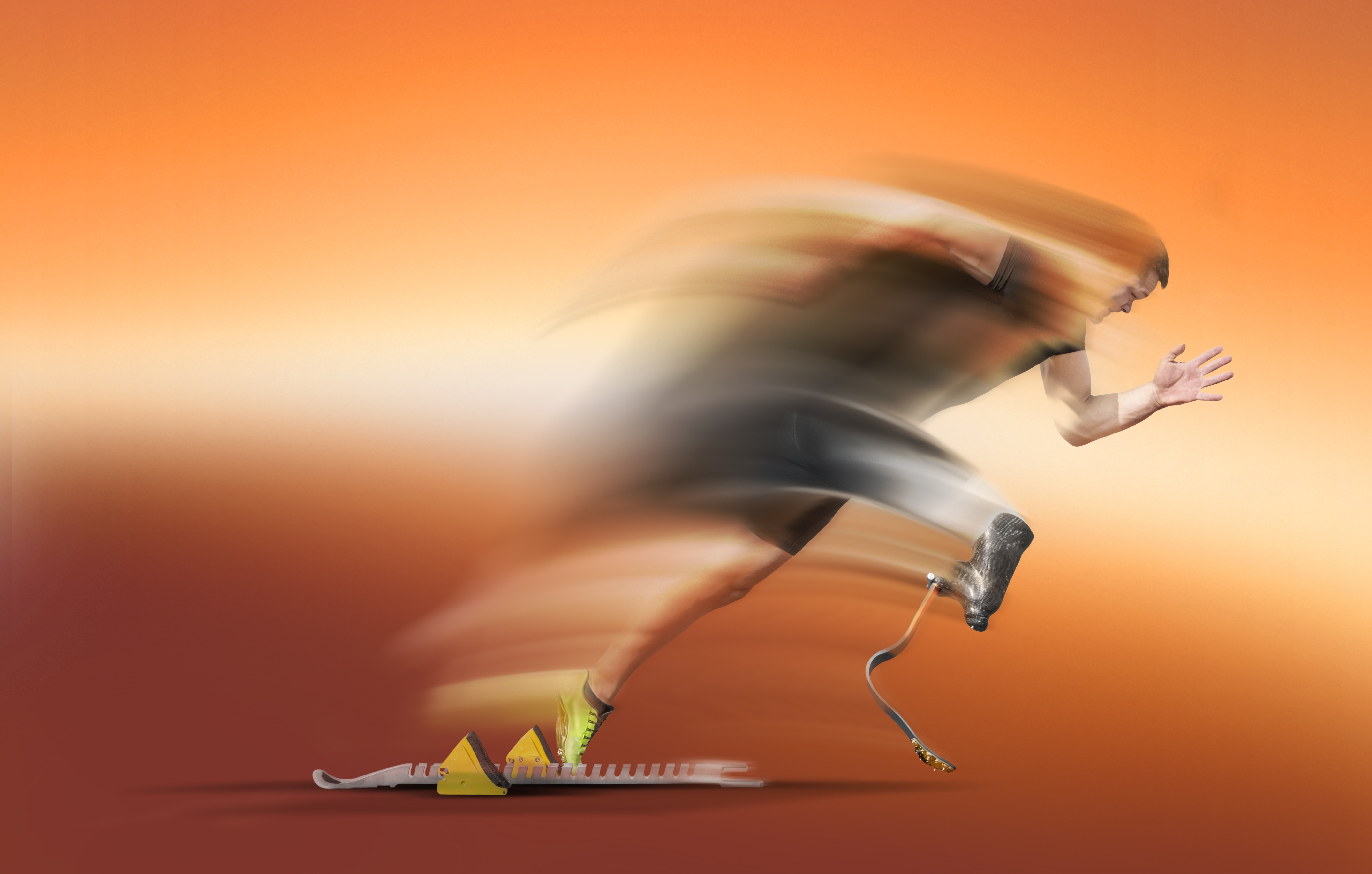 Explosive motion blurred start of an handicapped athlete out of the blocks with glowing running blades .