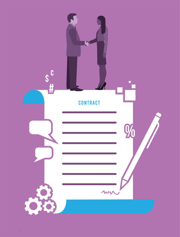 Two people stand on top of a contract and shake hands. 