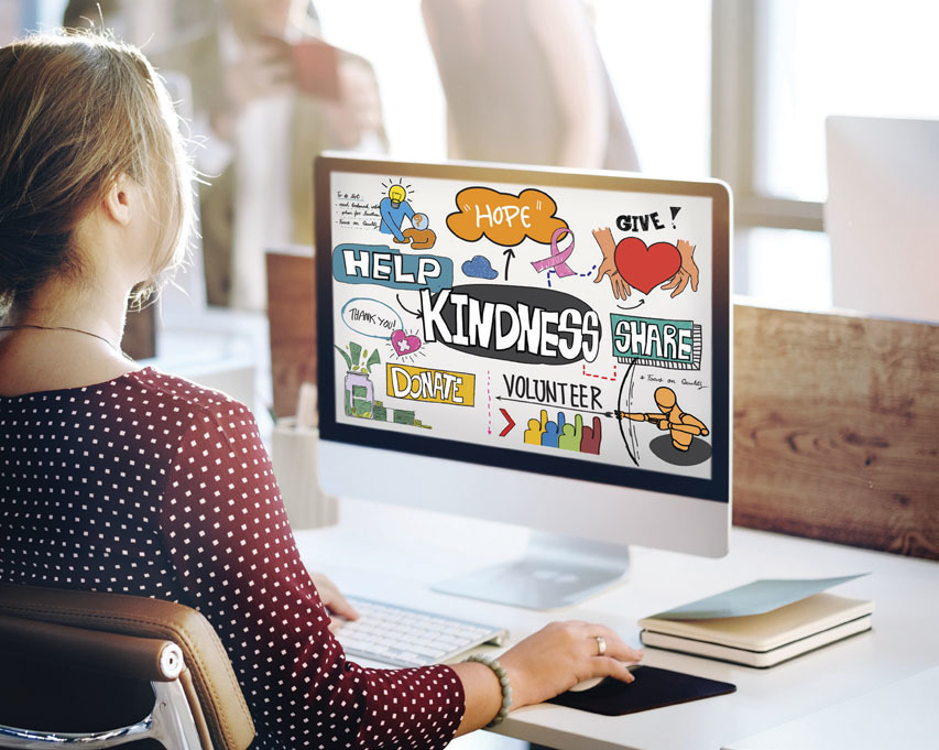 A woman looking at her computer which is full of positive messages: Hope, Help, Kindness, Share, Volunteer, Thank You.