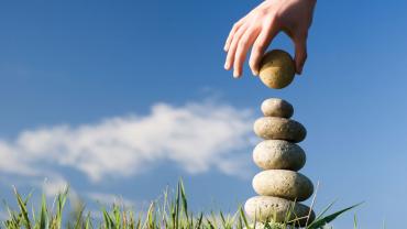 a hand building a stack of stones