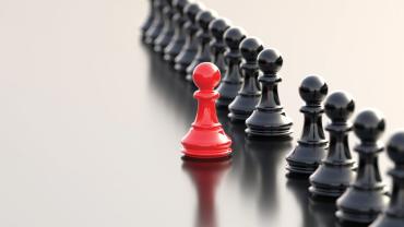 red chess piece standing out from black chess pieces