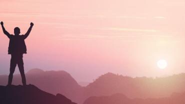 Person with both hands in the air at the top of a mountain