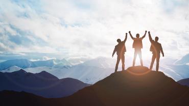 three business people on top of a mountain