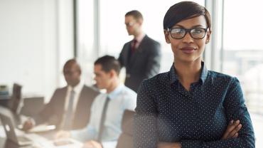 professional female in glasses in the foreground with three colleagues faded in the background
