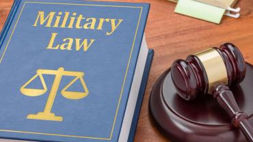 military law book and judge's gavel on a wooden desk