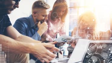 four employees gathered around a computer