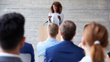 a young woman standing at a podium in front of an audience