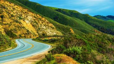 two lane road winding around hilly countryside 