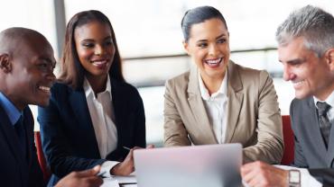 diverse professionals seated around a computer
