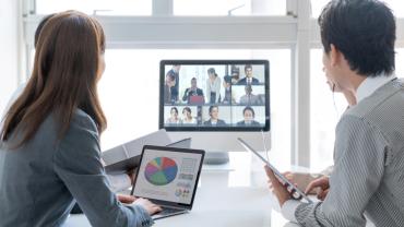 office workers gathered around a screen hosting a virtual meeting