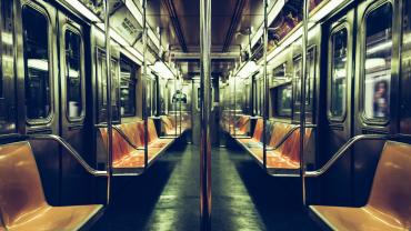 Interior of a dimly lit subway car with orange seats.