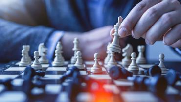 Close-up of businessman holding king chess piece on a black and white checkboard