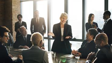 woman appearing to be leading group discussion, white, gray hair, diverse group