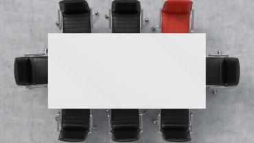 table with chairs around it and no one there, one red chair, the rest black -- symbolizing here the person who chose to cancel the meeting