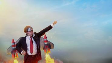 man, it appears, white, suited, propelled by jet engines, hand thrust toward sky