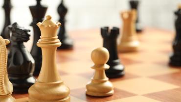 Black and white chess pieces facing each other on a chess board. 