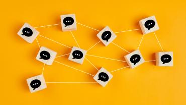 Wooden blocks with chat boxes drawn on them interconnected with strings. 