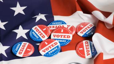 several i voted today buttons on an American flag