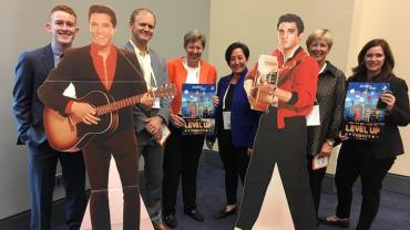 a photo of 6 people standing with 2 elvis cardboard figures