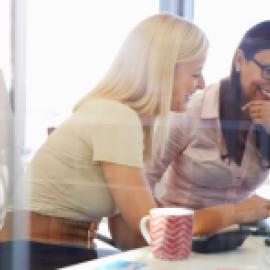 two professional woman seated together at a desk collaborating 