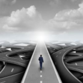  A man in a suit walking on a highway that has many directions. 