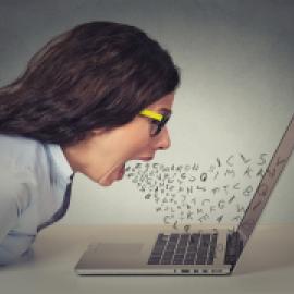 photo of woman, white skin, mouth open at laptop with letters coming out as though pouring out comments -- looks somewhat angry, frustrated,