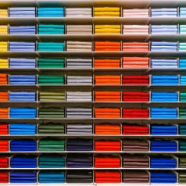 shirts oof many different colors stored in shelves within similar color palettes