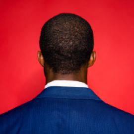 Man with his back turned towards a red background. 
