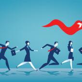 Several businesspeople following a leader with a large red flag