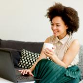a woman sitting on her couch and using a laptop