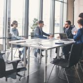 five professionals seated at a table in a meeting