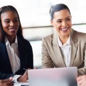 four diverse professionals seated at a table smiling