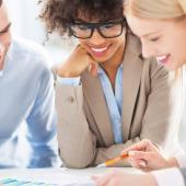 three professionals leaning on a table reviewing papers
