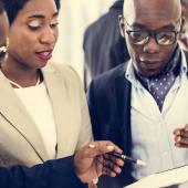 three standing professionals review a document together