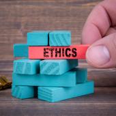 a hand stacks small blocks of one color and starts to pull another colored block with "Ethics" written on it. 