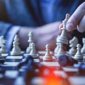 Close-up of businessman holding king chess piece on a black and white checkboard