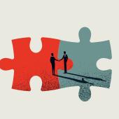 Two individuals shaking hands in agreement with two conjoined puzzle pieces as the backdrop. 