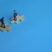 Two men facing each other on matching jigsaw pieces. 