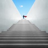 Image of stairs emerging from the ground, with an individual heroically standing at the top. 