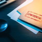 a folder marked confidential and a magnifying glass