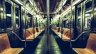Interior of a dimly lit subway car with orange seats.